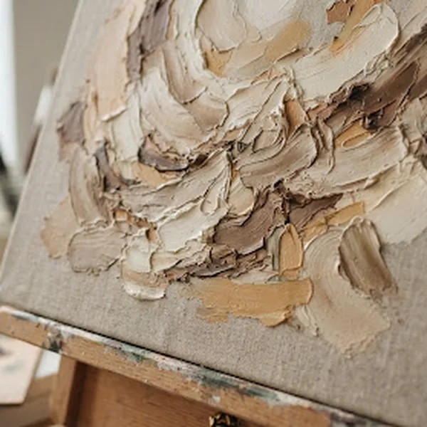 Close-up of a textured painting in progress, thick impasto strokes in beige, umber and soft white